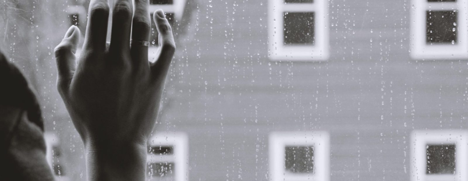 Nainen katselee sateeseen ikkunasta