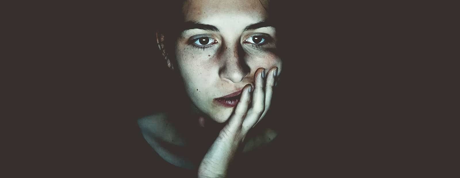 nainen pimeässä käsi poskella