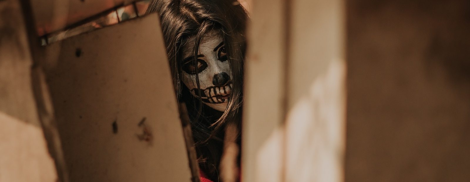 kasvomaalattu nainen kurkistaa hyllyjen välistä